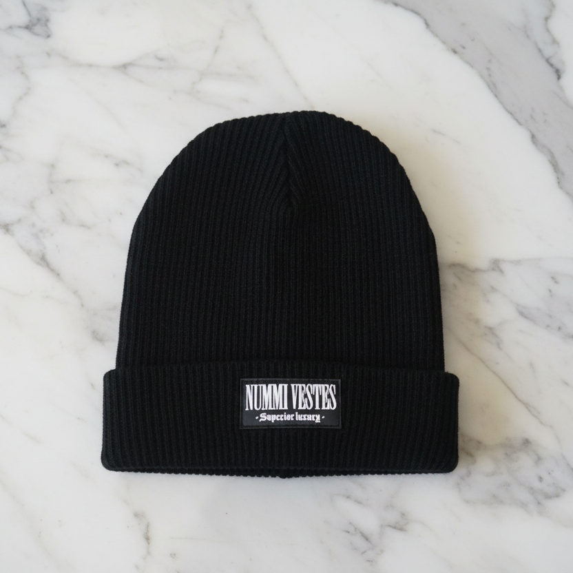 Black beanie with a brand label on a marble surface