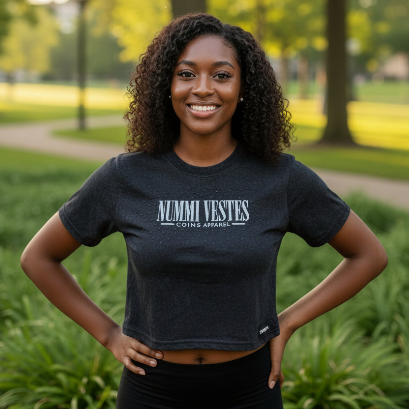 A woman wearing a NUMMI VESTES black acid-washed cotton crop t-shirt with graphic branding in a park setting.