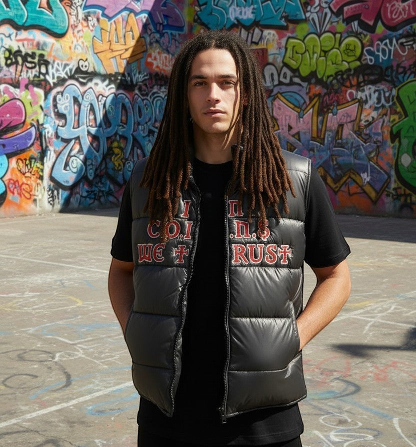 A model wearing a black NUMMI VESTES puffer vest with red embroidered lettering against a graffiti wall background.