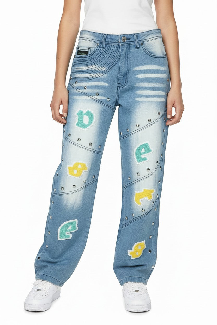 NUMMI VESTES blue denim boyfriend jeans with silver stud hems, chenille lettering, and embroidered leg details.