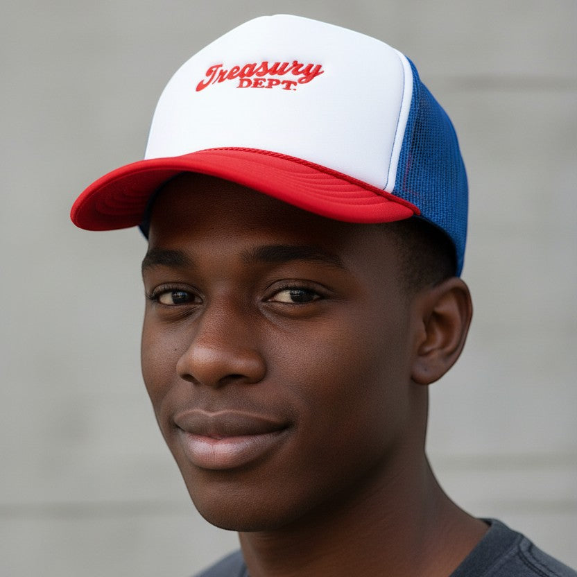 A man wearing a NUMMI VESTES foam trucker snapback with a white front, red brim, and blue mesh back.