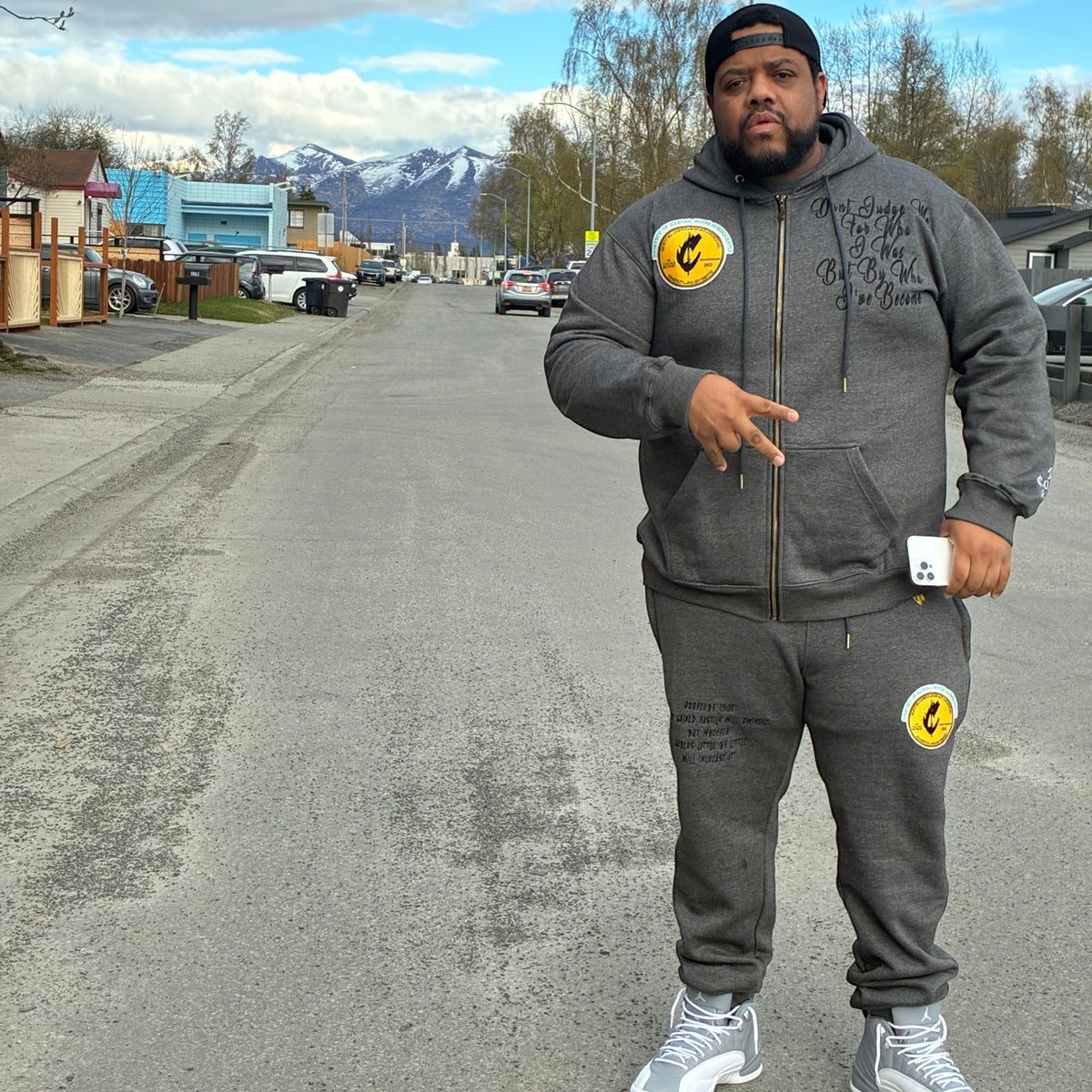 Man wearing a NUMMI VESTES grey zippered hooded sweatsuit with yellow circular patches and black text detailing